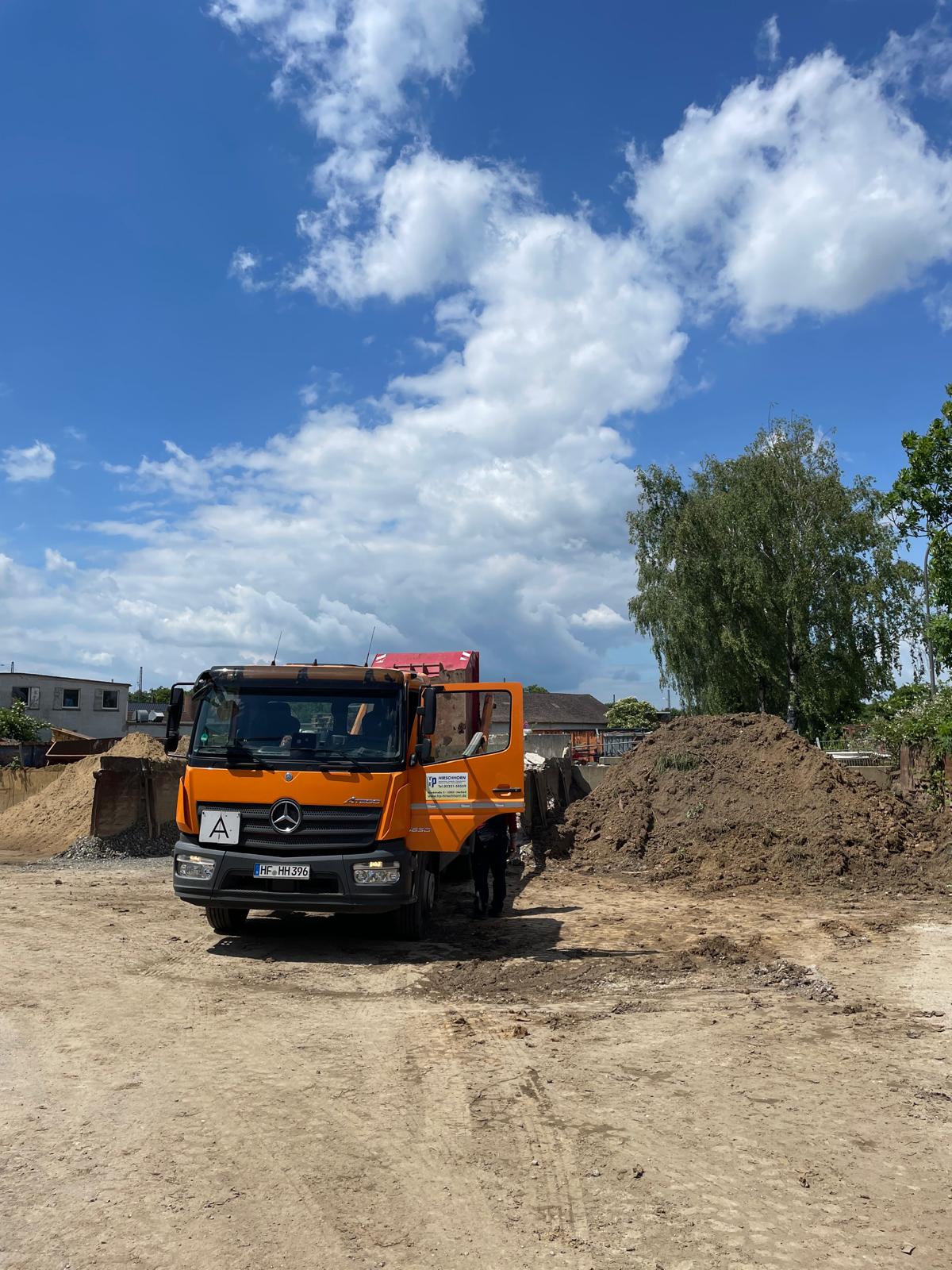 Orangefarbener Kipper-LKW von H. + P. Hirschhorn auf dem Betriebshof in Herford