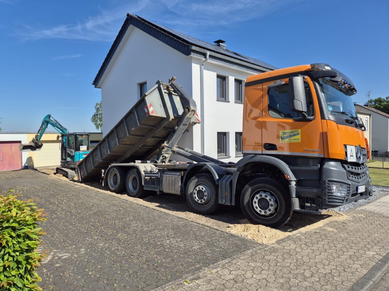 Hirschhorn-Containerdienst stellt einen Abrollcontainer an einer Einfahrt in Herford, Minibagger im Einsatz